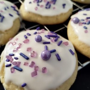 Ricotta cheese cookies with purple sprinkles on a cooling rack.
