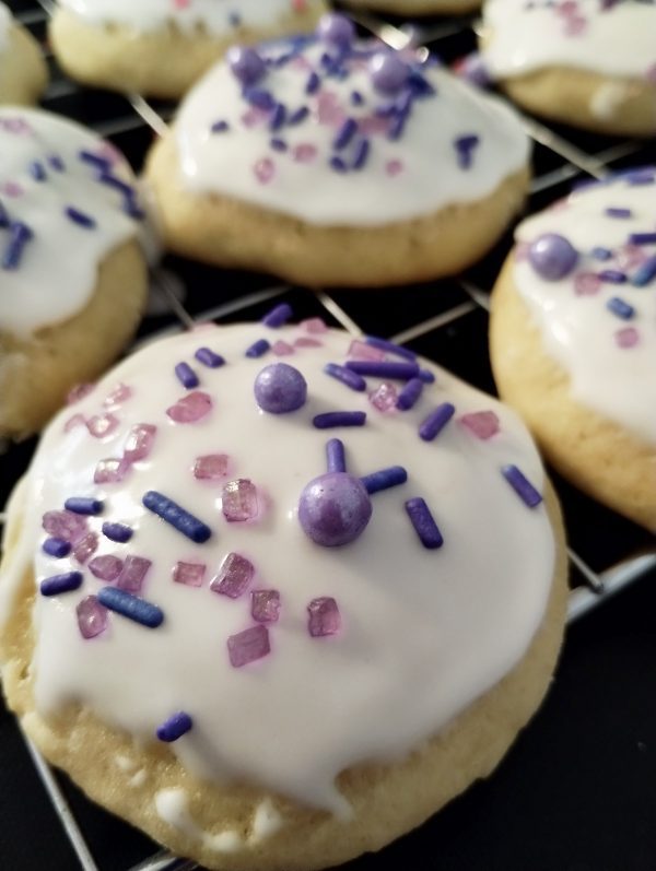 Ricotta cheese cookies with purple sprinkles on a cooling rack.
