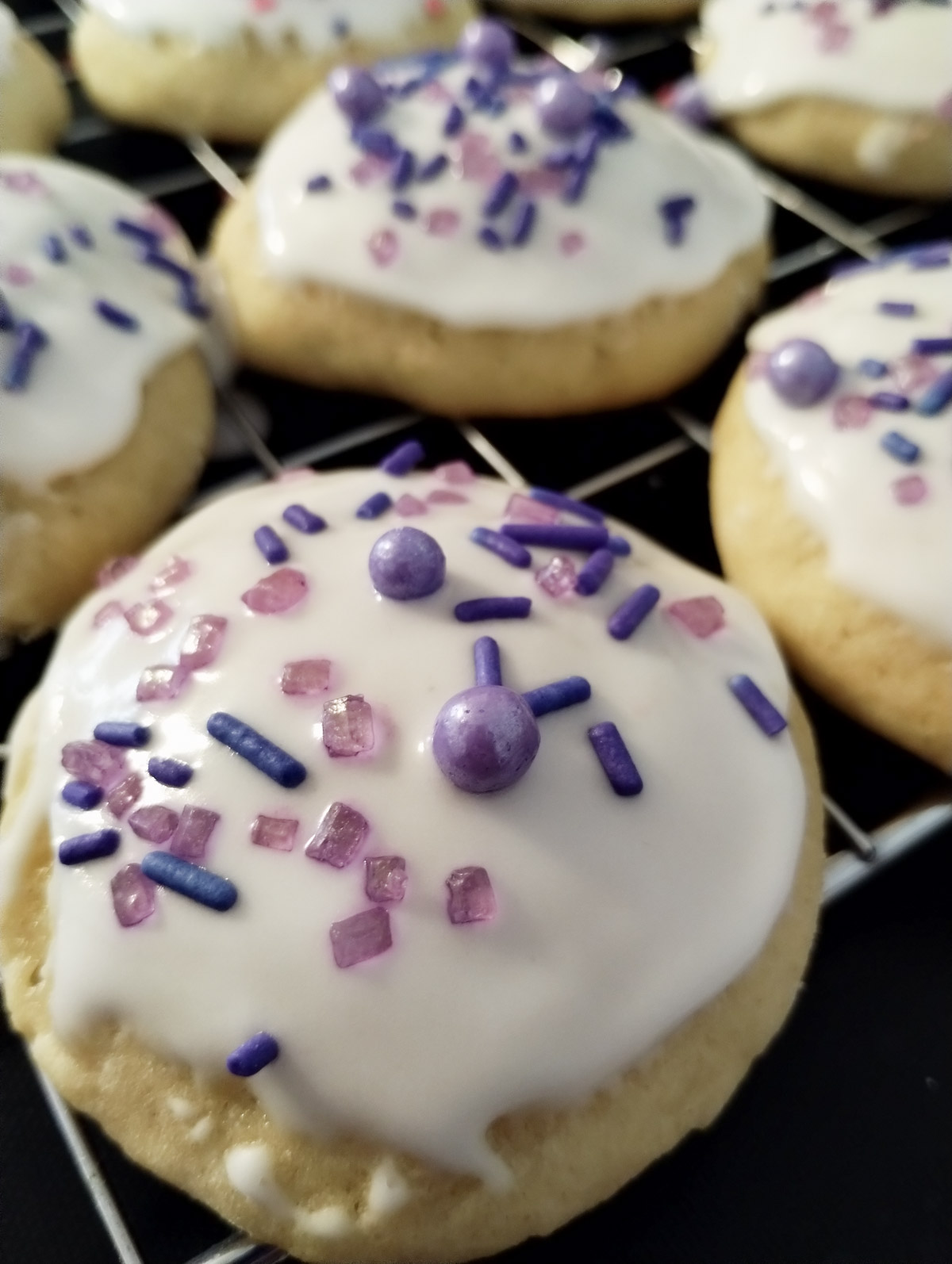 Ricotta cheese cookies with purple sprinkles on a cooling rack.