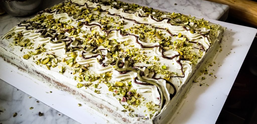 16 × 12-inch Italian pistachio cake with creamy buttercream, pistachio cream, chocolate, and crushed pistachios on a cake board.